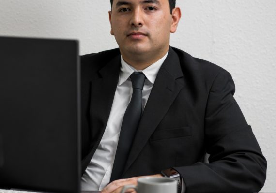man in black suit jacket holding white ceramic mug