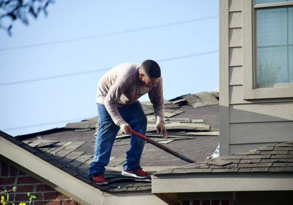 a man with a hammer on top of a roof