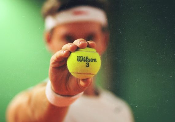 person holding green Wilson tennis ball